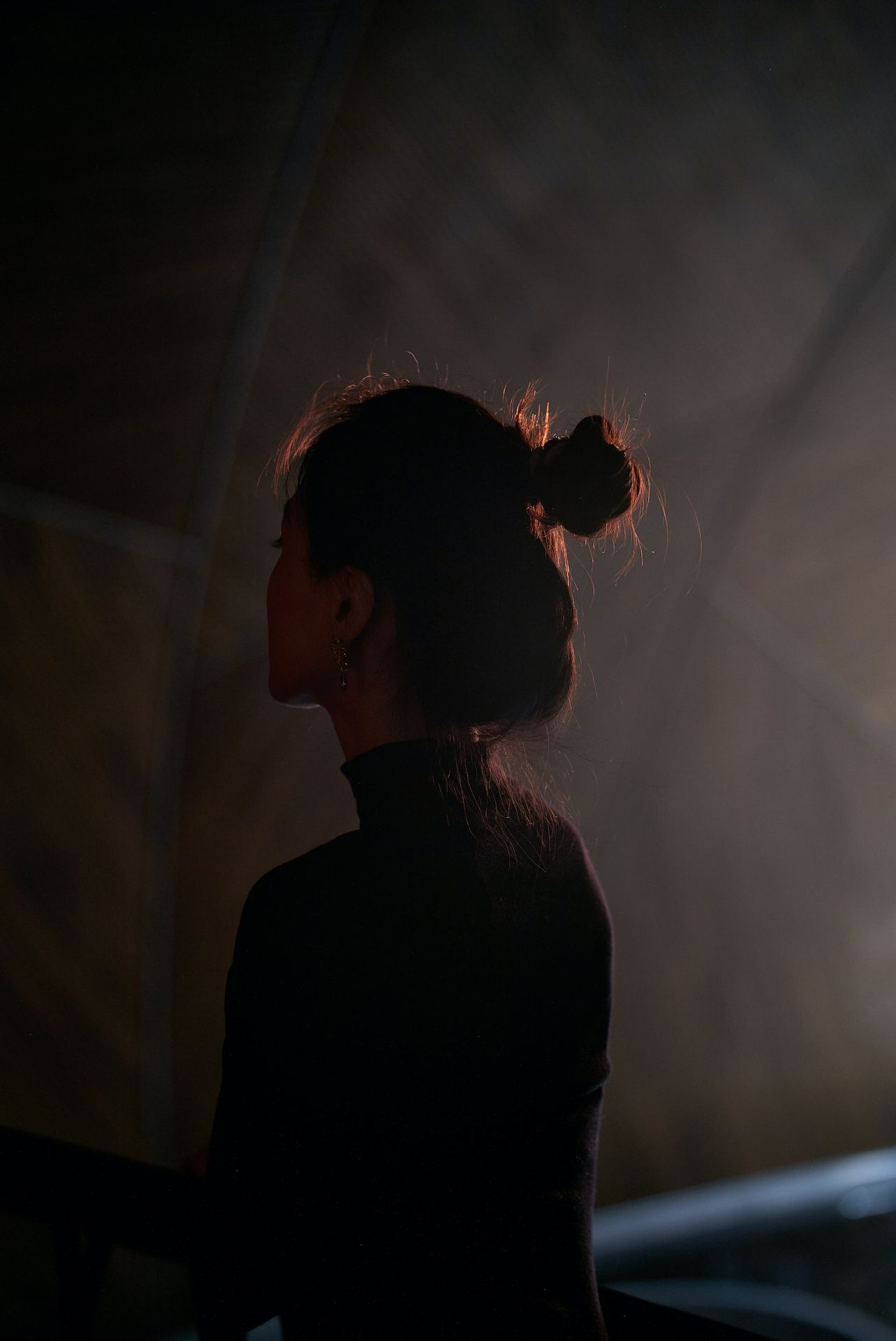 a woman with a ponytail standing in the dark